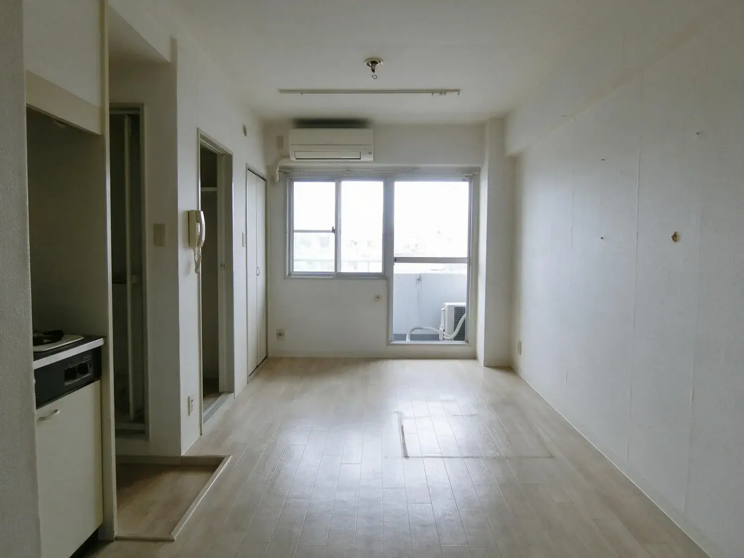 Before and after of an empty 22 square metre shibuya 1k, the entire flat one room, photographed the way it is handed over after move-out cleaning — original listing photo before editing