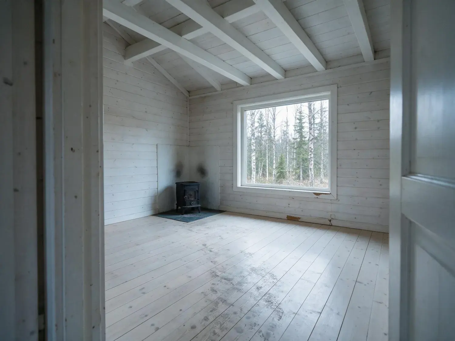 Before and after of a blackened-larch scandinavian cabin interior, a blank pale-wood shell transformed into a serene nordic retreat — original listing photo before editing