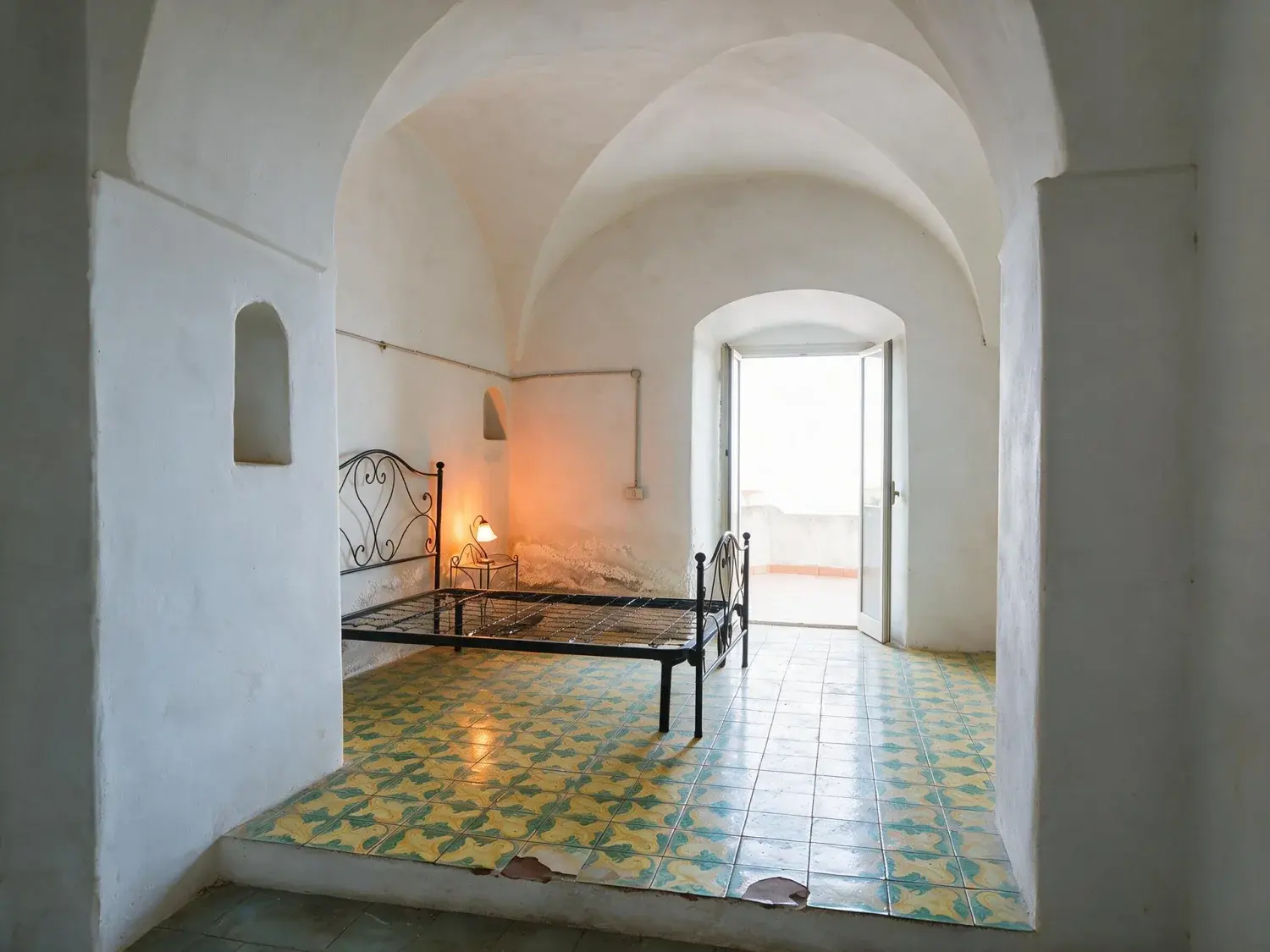 Before and after of a dark vaulted room on the amalfi coast with its exposure, mixed lighting and blown doorway corrected — enhanced by Plotpane