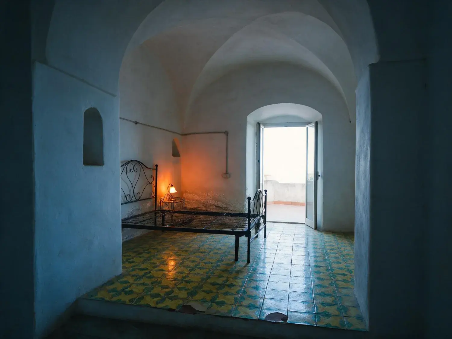Before and after of a dark vaulted room on the amalfi coast with its exposure, mixed lighting and blown doorway corrected — original listing photo before editing