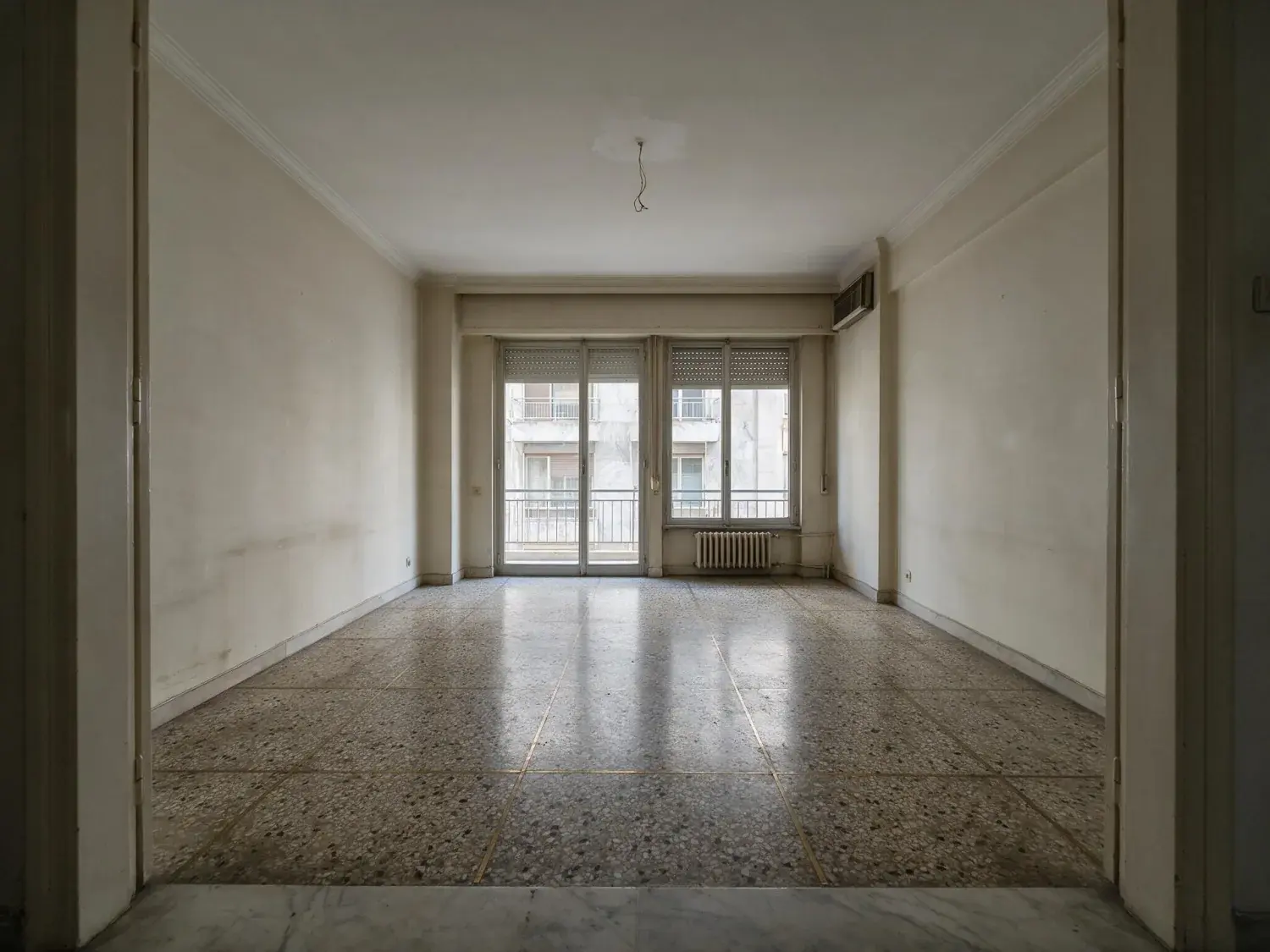 Before and after of an empty kolonaki living room furnished as a mediterranean short-let — original listing photo before editing