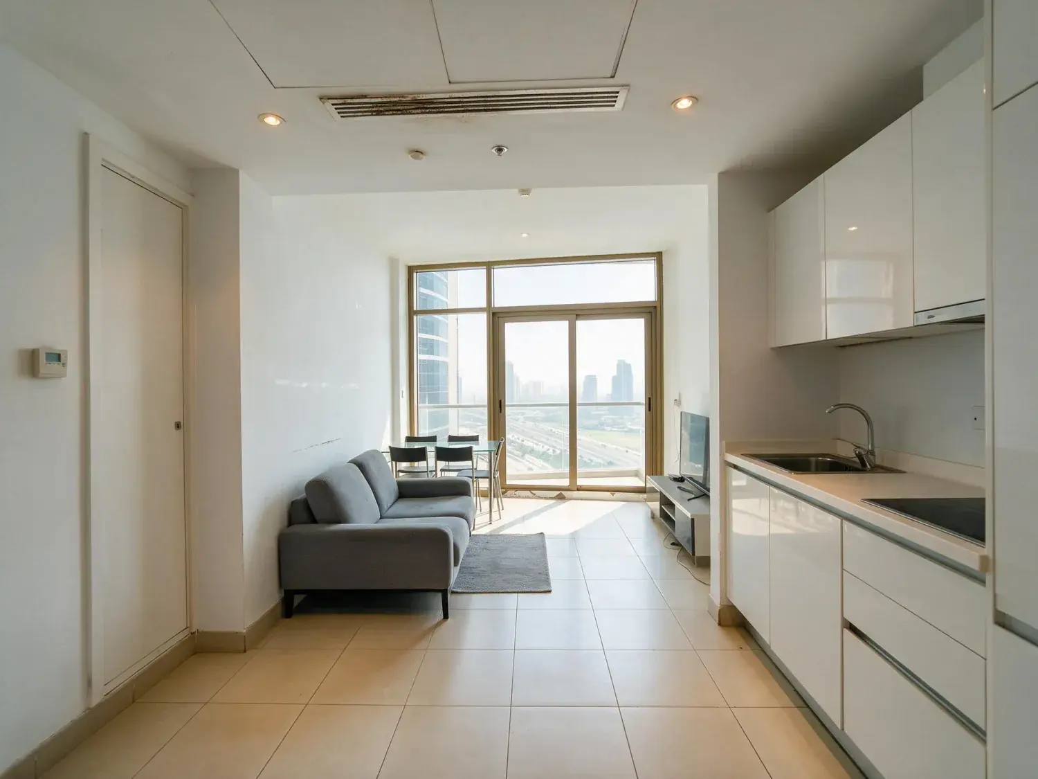 Before and after of a landlord-furnished downtown dubai one-bed shot into the window, so the room sits dark and the glass is blown out — enhanced by Plotpane