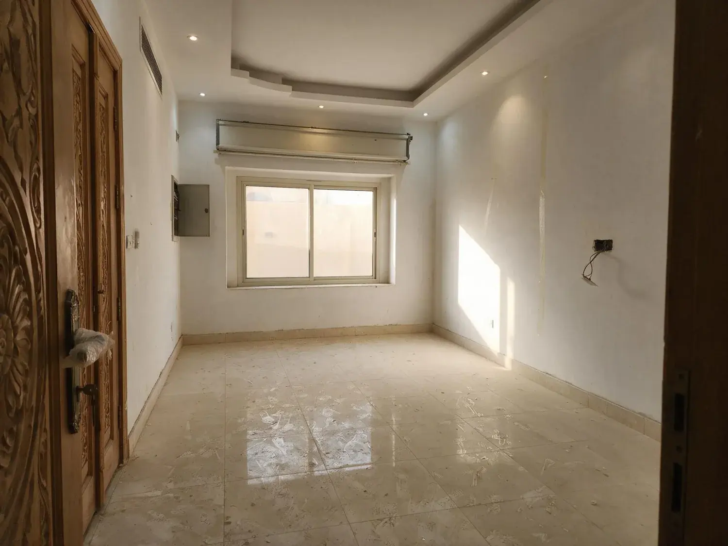 Before and after of an empty majlis in a just-handed-over riyadh villa, furnished so a buyer can see how the room takes seating — original listing photo before editing