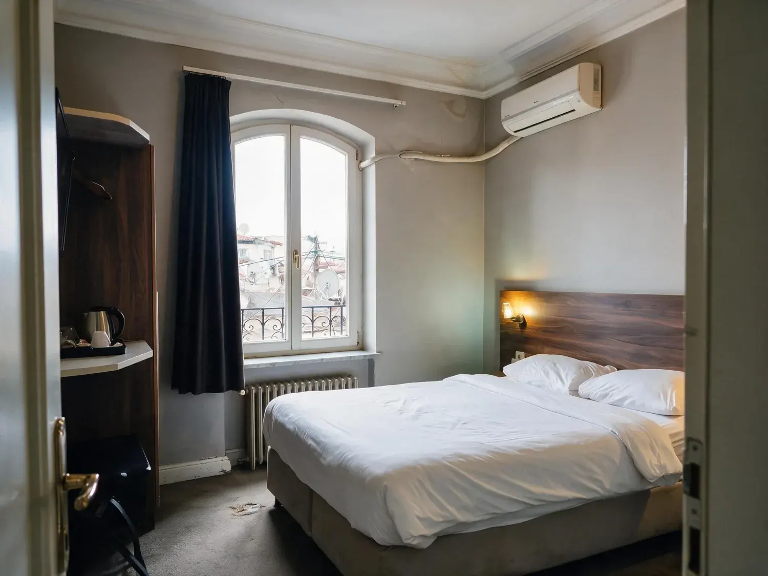 Before and after of a guest room in a converted karaköy han shot on a phone, with the window blown to white and the rest of the room sunk in shadow — enhanced by Plotpane