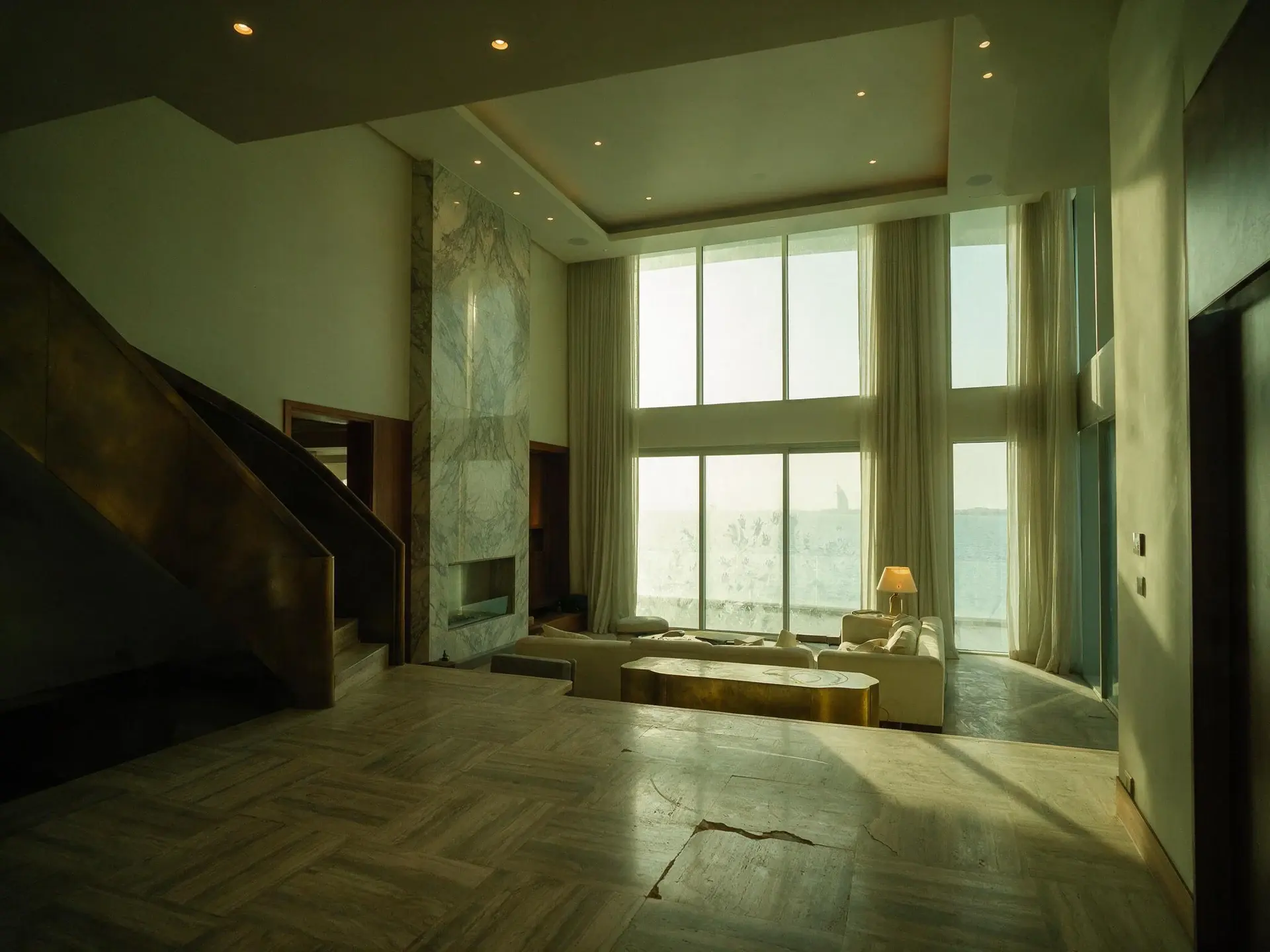 Before and after of a Jumeira Bay Island waterfront mansion living room in Dubai. — original listing photo before editing