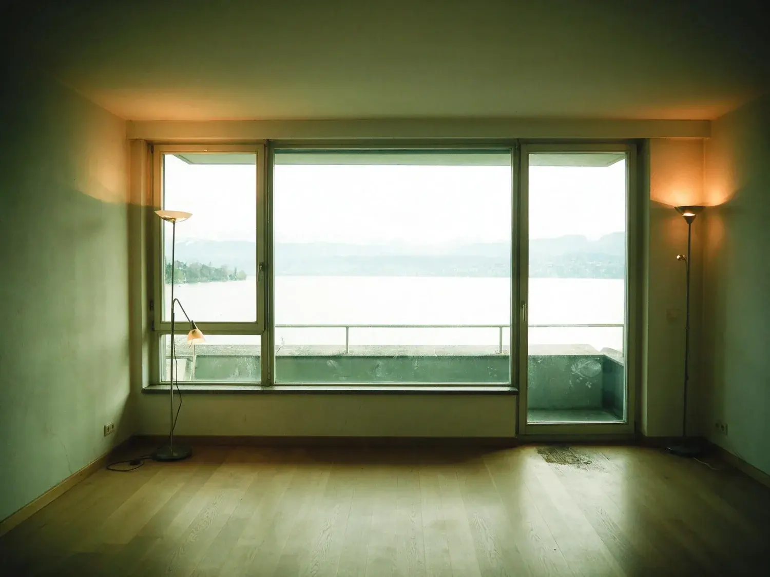 Before and after of a Seefeld lakeside flat, dim with the lake glare unmanaged. — original listing photo before editing