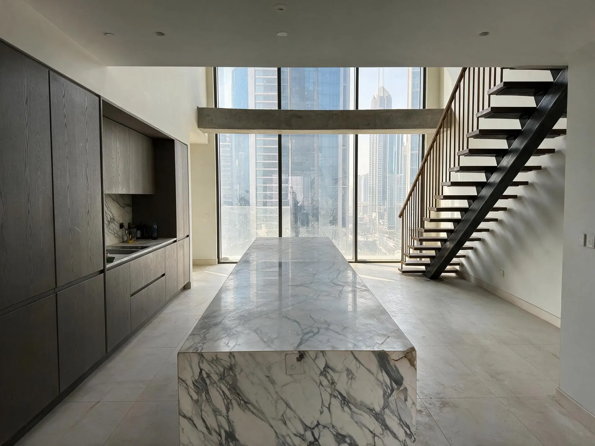 Before and after of a cluttered marble kitchen in a DIFC Index Tower penthouse, Dubai. — enhanced by Plotpane