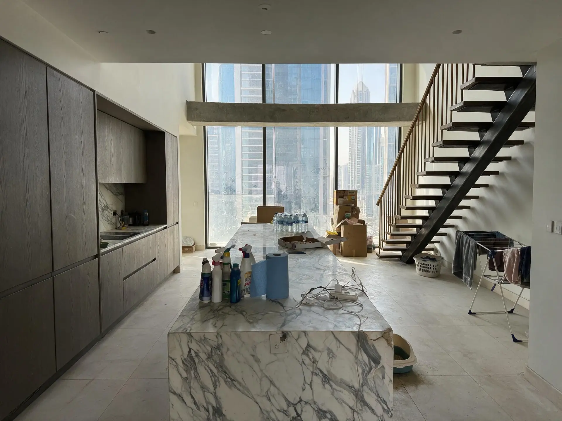 Before and after of a cluttered marble kitchen in a DIFC Index Tower penthouse, Dubai. — original listing photo before editing