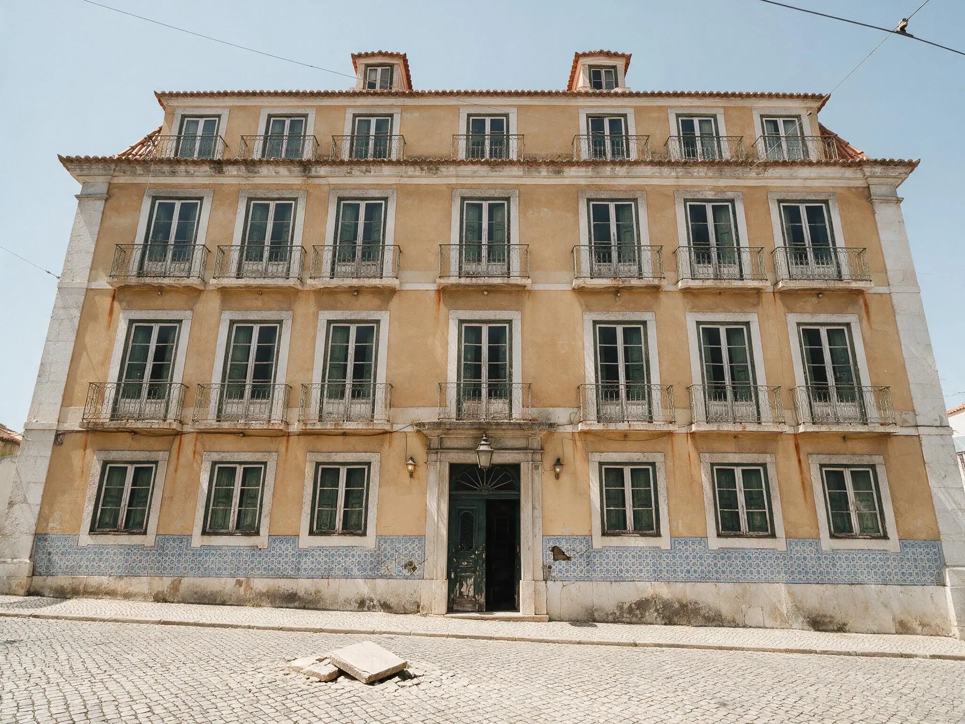 Before and after of a Pombaline apartment building facade in Príncipe Real, Lisbon, taken to dusk. — original listing photo before editing
