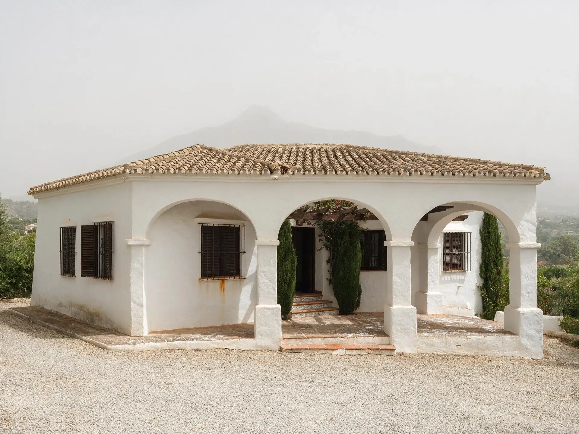 Before and after of an Andalusian villa exterior in Nueva Andalucía, Marbella, with the sky replaced. — original listing photo before editing