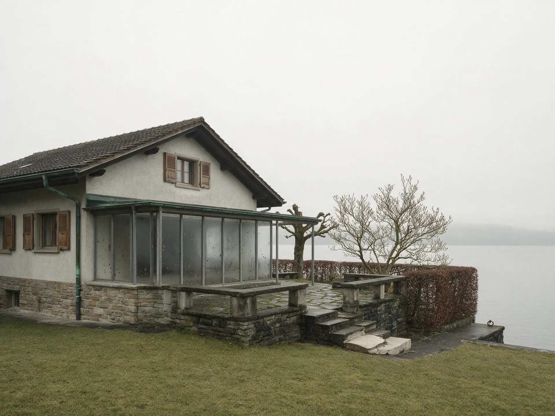 Before and after of a lakeside house exterior on the Zurich Goldküste with the sky replaced. — original listing photo before editing