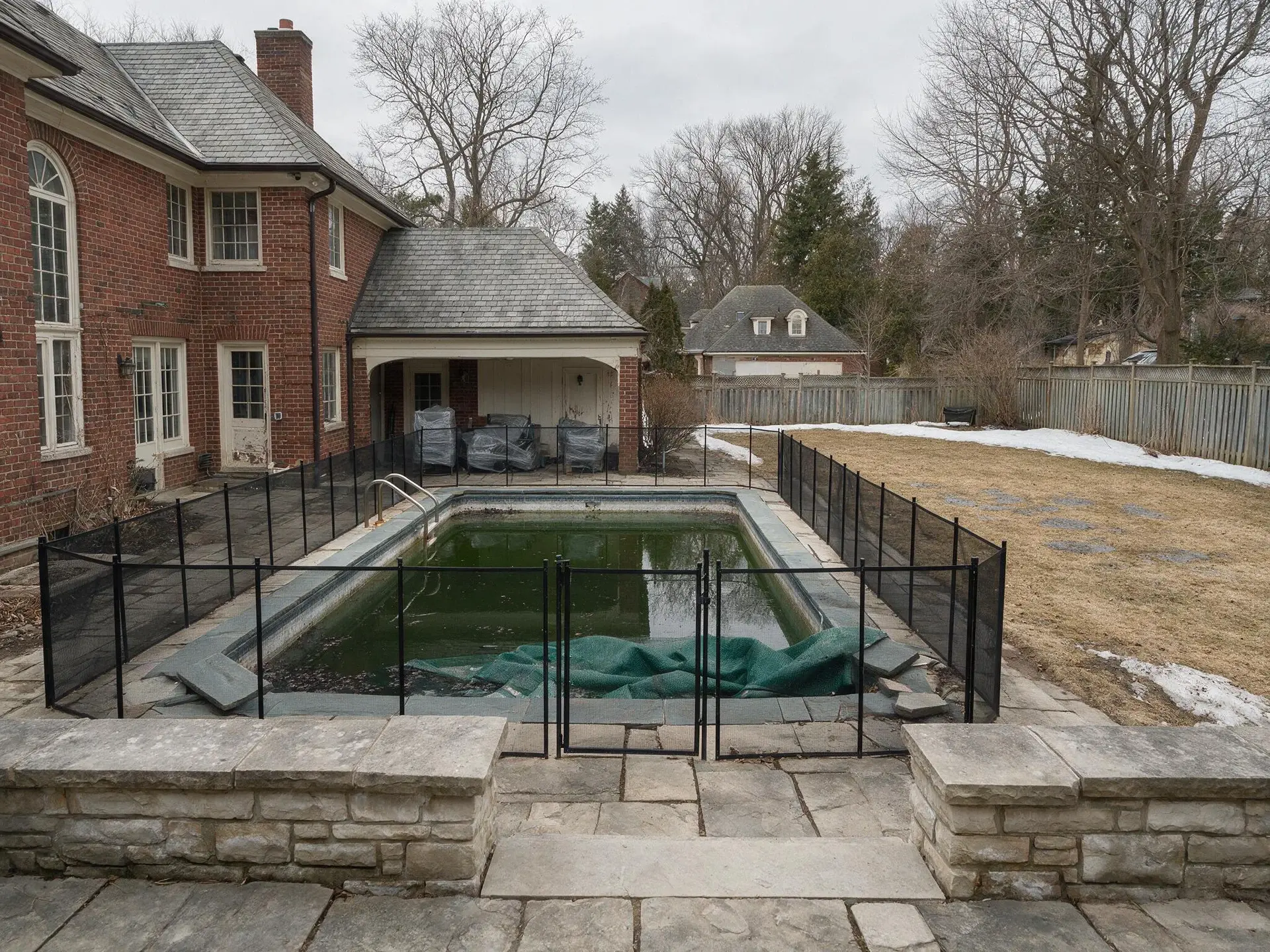 Before and after of the back garden and pool of a Forest Hill house in Toronto after winter. — original listing photo before editing