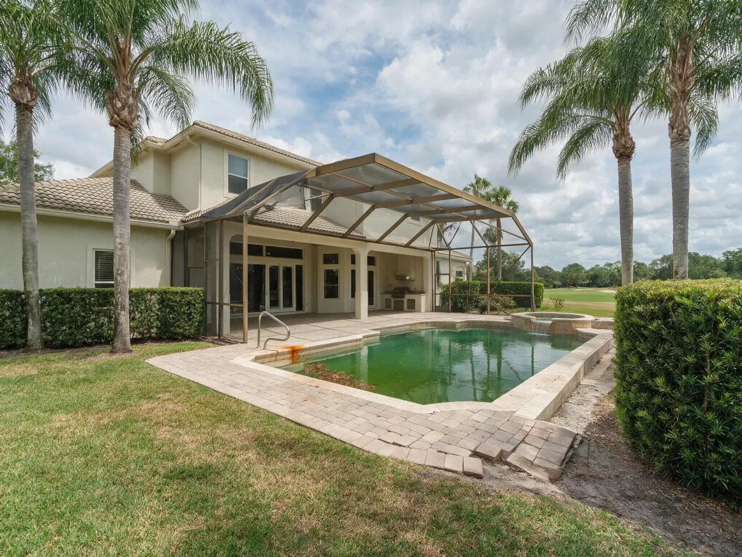 Before and after of rear exterior of a lake nona golf & country club estate with heat-stressed st. augustine lawn and green-tinged pool recovered to healthy turf and clear caribbean-blue water — original listing photo before editing