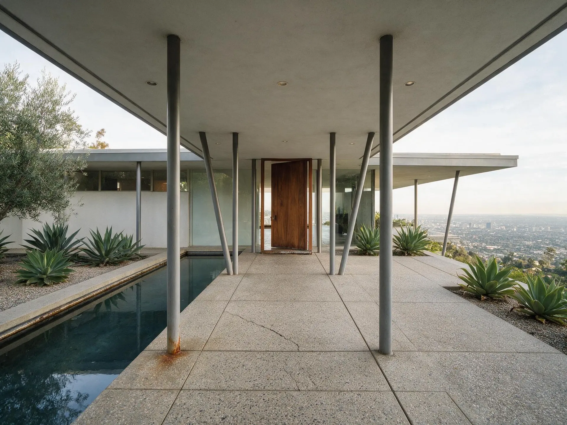 Before and after of a post-and-beam entry colonnade at a Trousdale Estates house in Beverly Hills. — original listing photo before editing