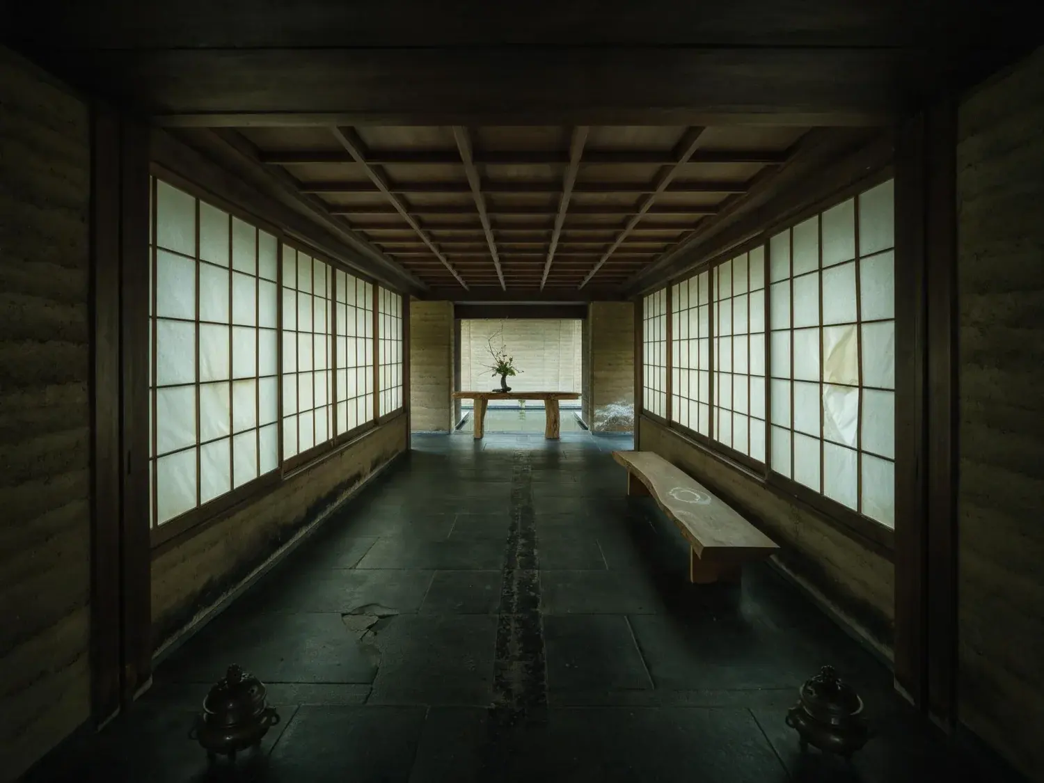 Before and after of an aman-quiet arrival lobby of dark stone and rice-paper light resolves into editorial clarity, every grain of its ink-black floor alive — original listing photo before editing