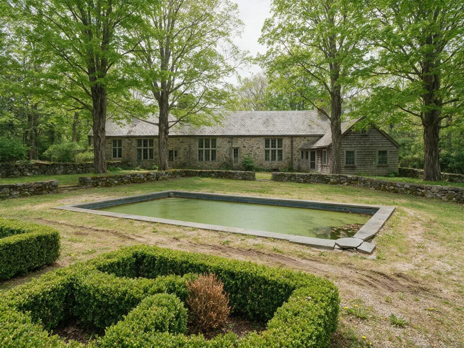 Before and after of a hand-laid stone manor in greenwich back-country commands a restored emerald meadow, its pool a polished slate rectangle in the turf — original listing photo before editing