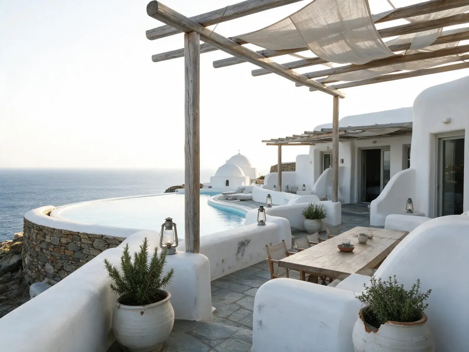 Before and after of a whitewashed cycladic hotel terrace tips into a cinematic aegean dusk, lanterns waking along its curved infinity pool — original listing photo before editing