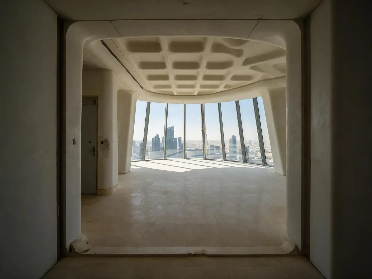Before and after of a penthouse crowning a parametric kafd tower in riyadh, its living core reimagined from bare concrete shell into a najdi-modernist salon — original listing photo before editing
