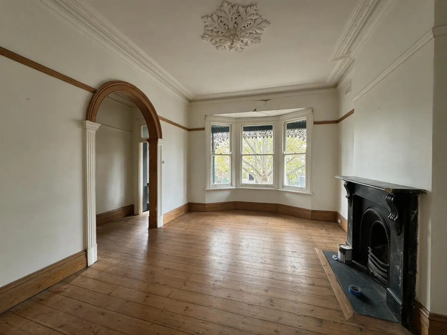 Before and after of a vacant front lounge of a single-fronted victorian terrace on a leafy south yarra street staged into the belle / vogue living australia auction-campaign hero — original listing photo before editing