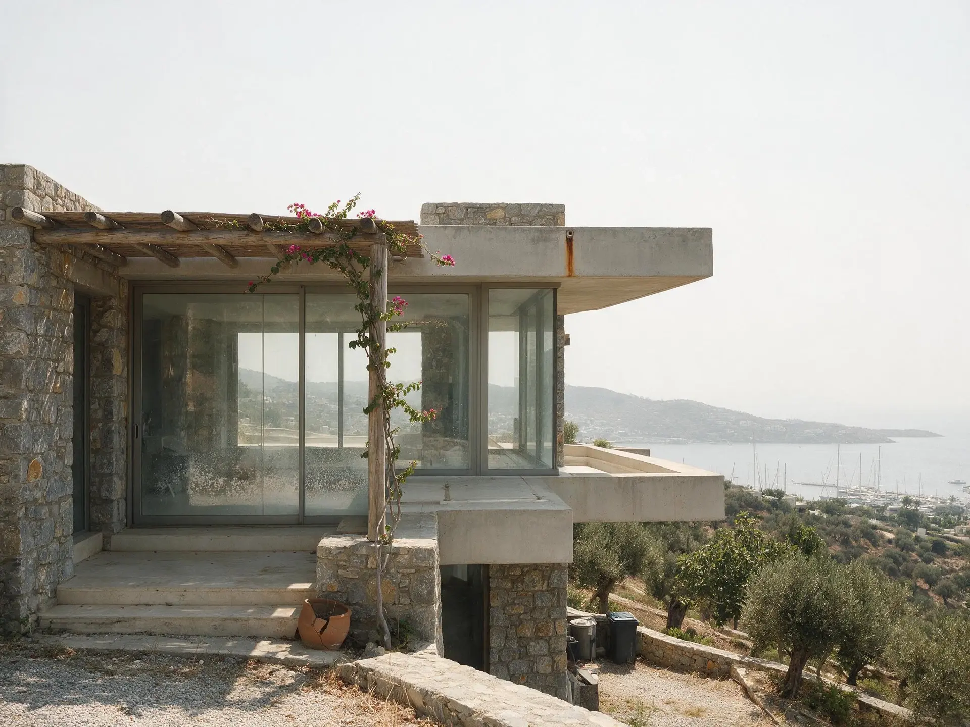 Before and after of a stone and glass villa exterior in Yalikavak, Bodrum, with the sky replaced. — original listing photo before editing