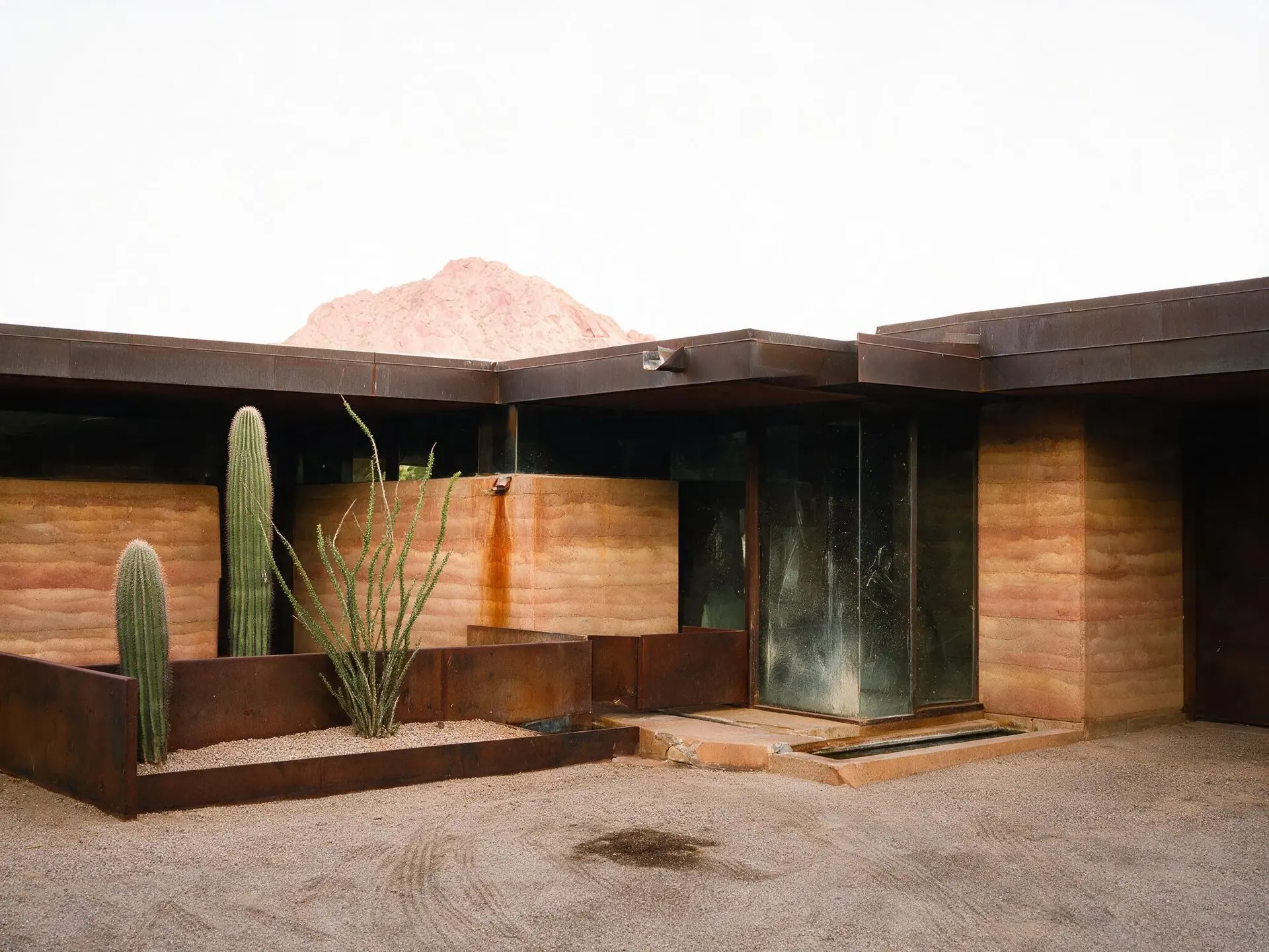 Before and after of a rammed-earth desert house below Camelback Mountain in Paradise Valley, Arizona. — original listing photo before editing