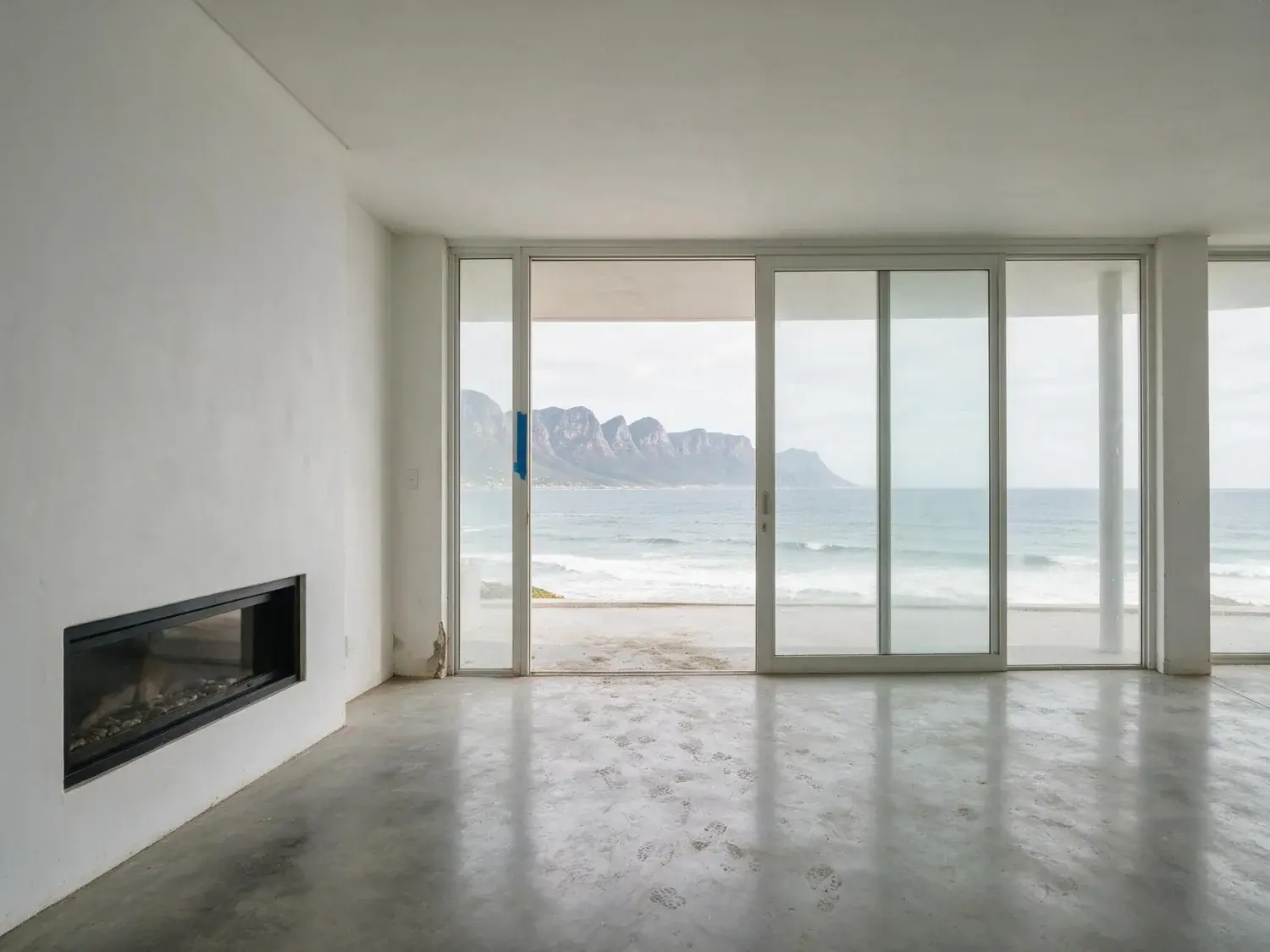Before and after of an empty Clifton living room facing the Atlantic and the Twelve Apostles. — original listing photo before editing