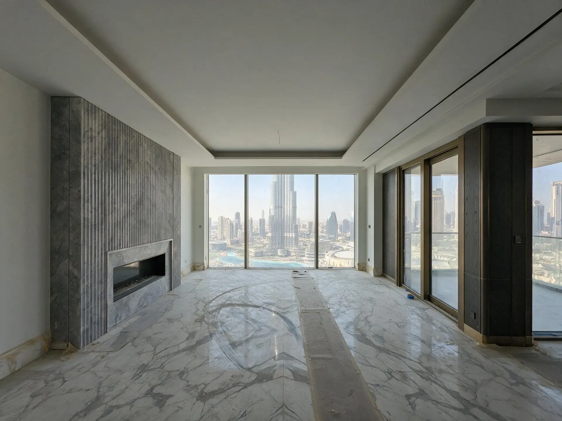 Before and after of an empty Burj Khalifa view penthouse living room in Downtown Dubai. — original listing photo before editing