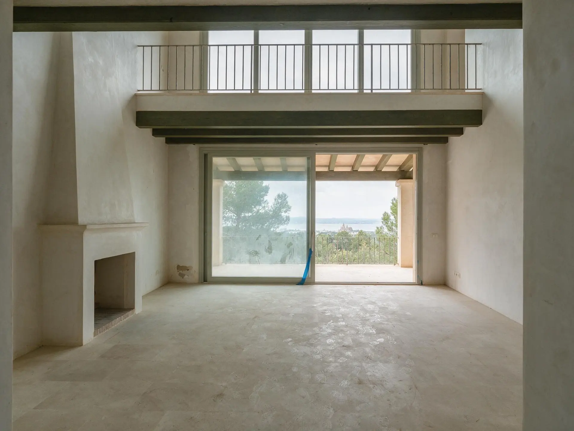 Before and after of an empty double-height salon in a Son Vida villa, Palma de Mallorca. — original listing photo before editing