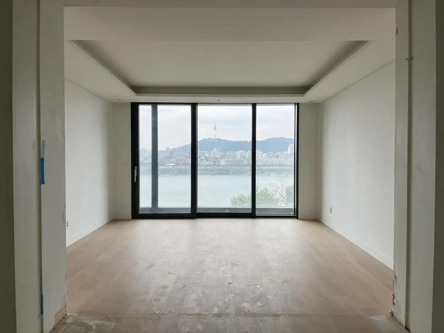 Before and after of an empty Hannam-dong living room over the Han river. — original listing photo before editing