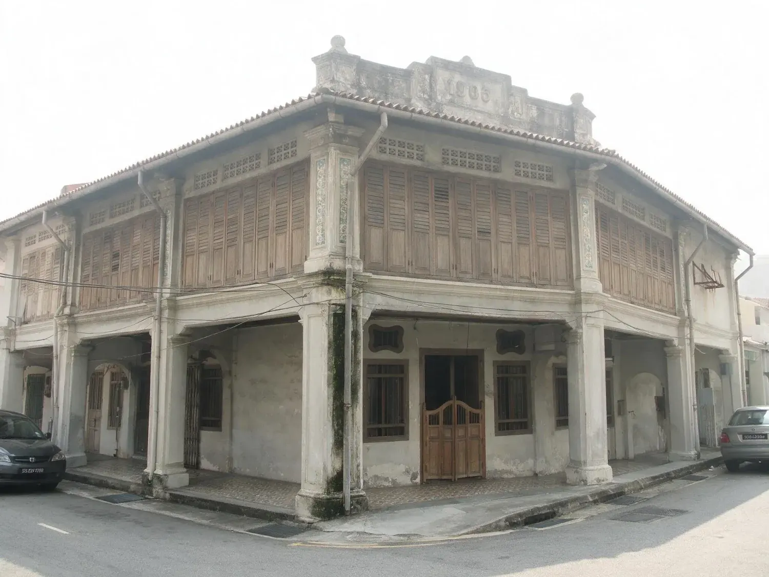 Before and after of a joo chiat shophouse facade shot under the flat white haze singapore has most middays, with no detail left in the sky at all — original listing photo before editing