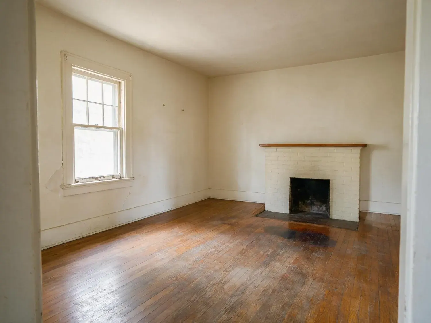 Before and after of empty west campus 1920s bungalow living room staged with warm mid-century furniture appropriate for ut graduate students and young austin professionals — original listing photo before editing