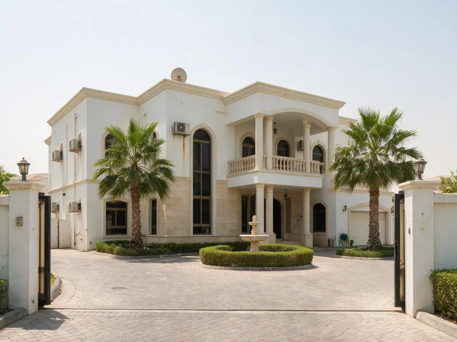 Before and after of an emirates hills villa front elevation shot at flat 2pm, with the windows dark and every exterior light off — original listing photo before editing