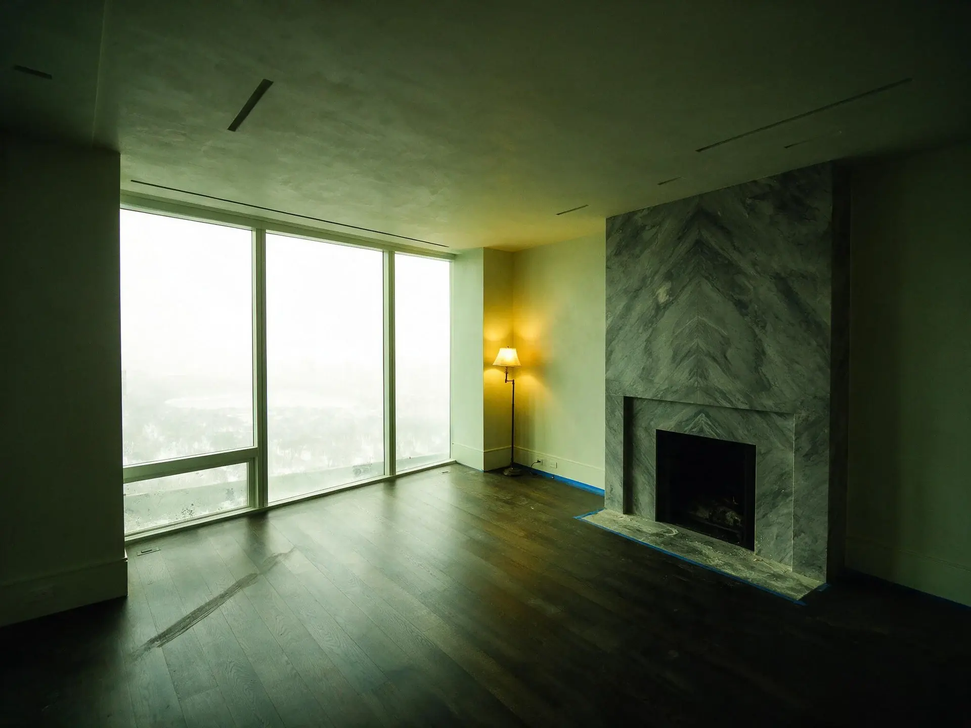 Before and after of a Billionaires' Row penthouse great room in New York facing Central Park — original listing photo before editing
