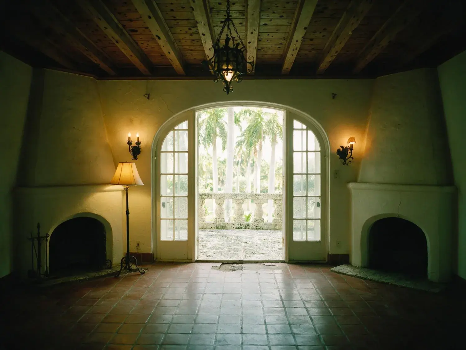 Before and after of a Coral Gables living room, dim with the arched openings burnt out. — original listing photo before editing