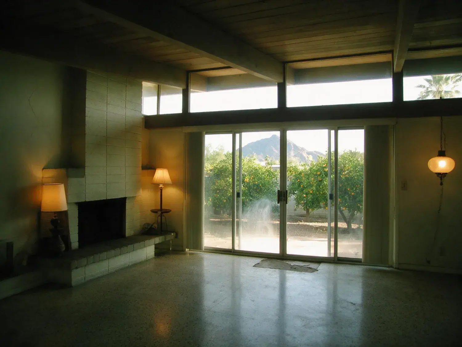 Before and after of an Arcadia ranch living room, dim inside against harsh desert glare outside. — original listing photo before editing