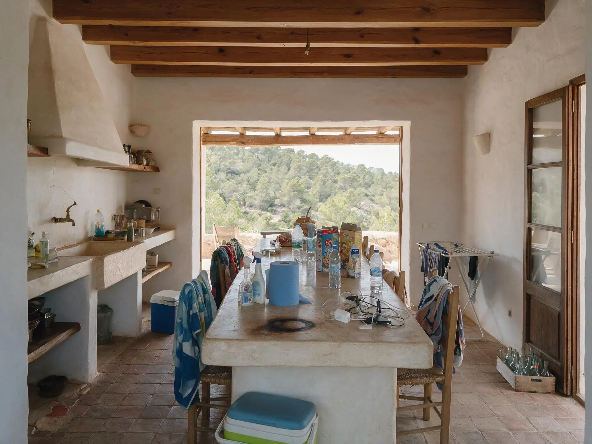 Before and after of a stone finca kitchen and great room in San Jose, Ibiza, with clutter removed. — original listing photo before editing