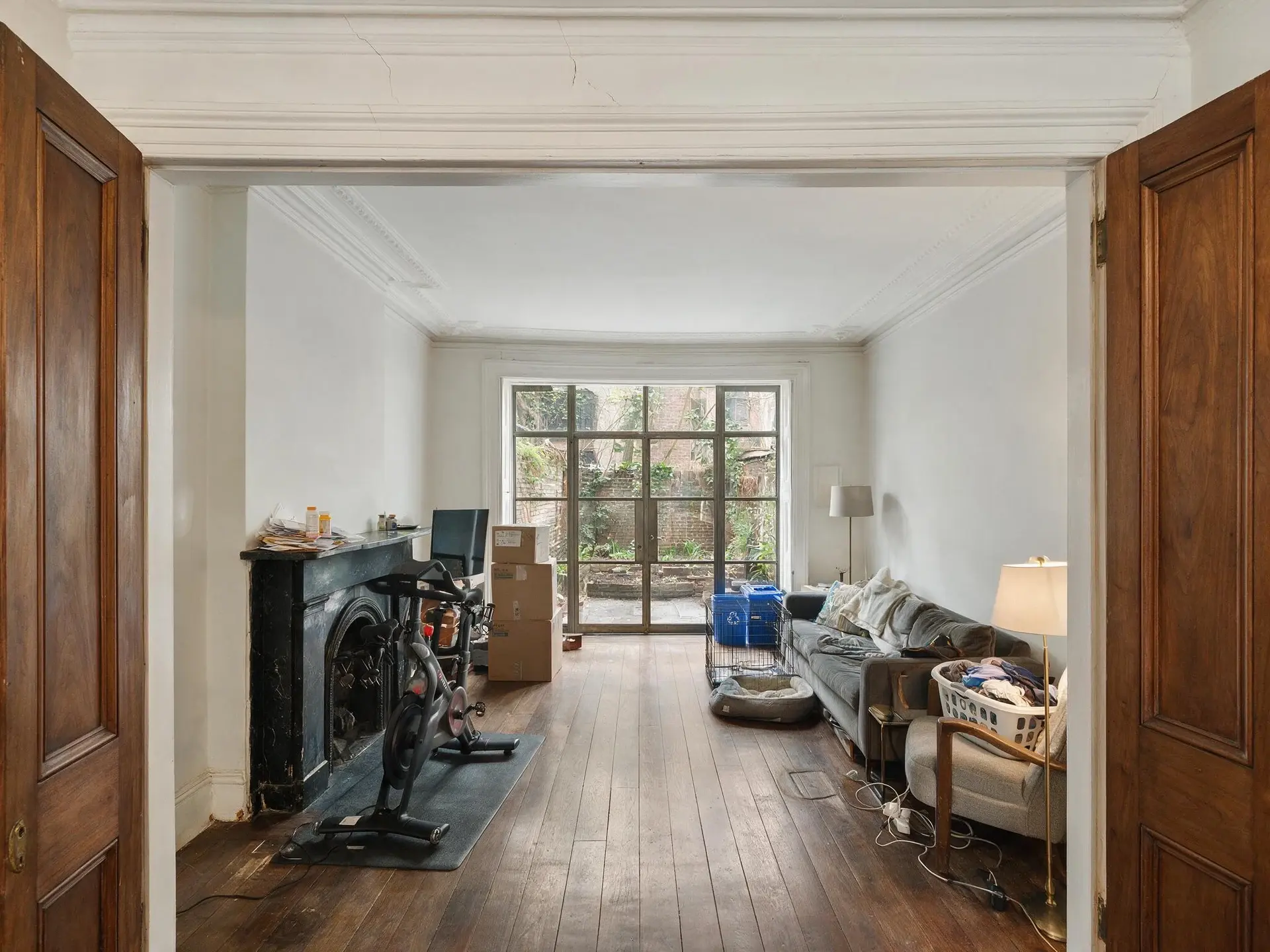 Before and after of a West Village townhouse parlor in New York with owner clutter removed — original listing photo before editing