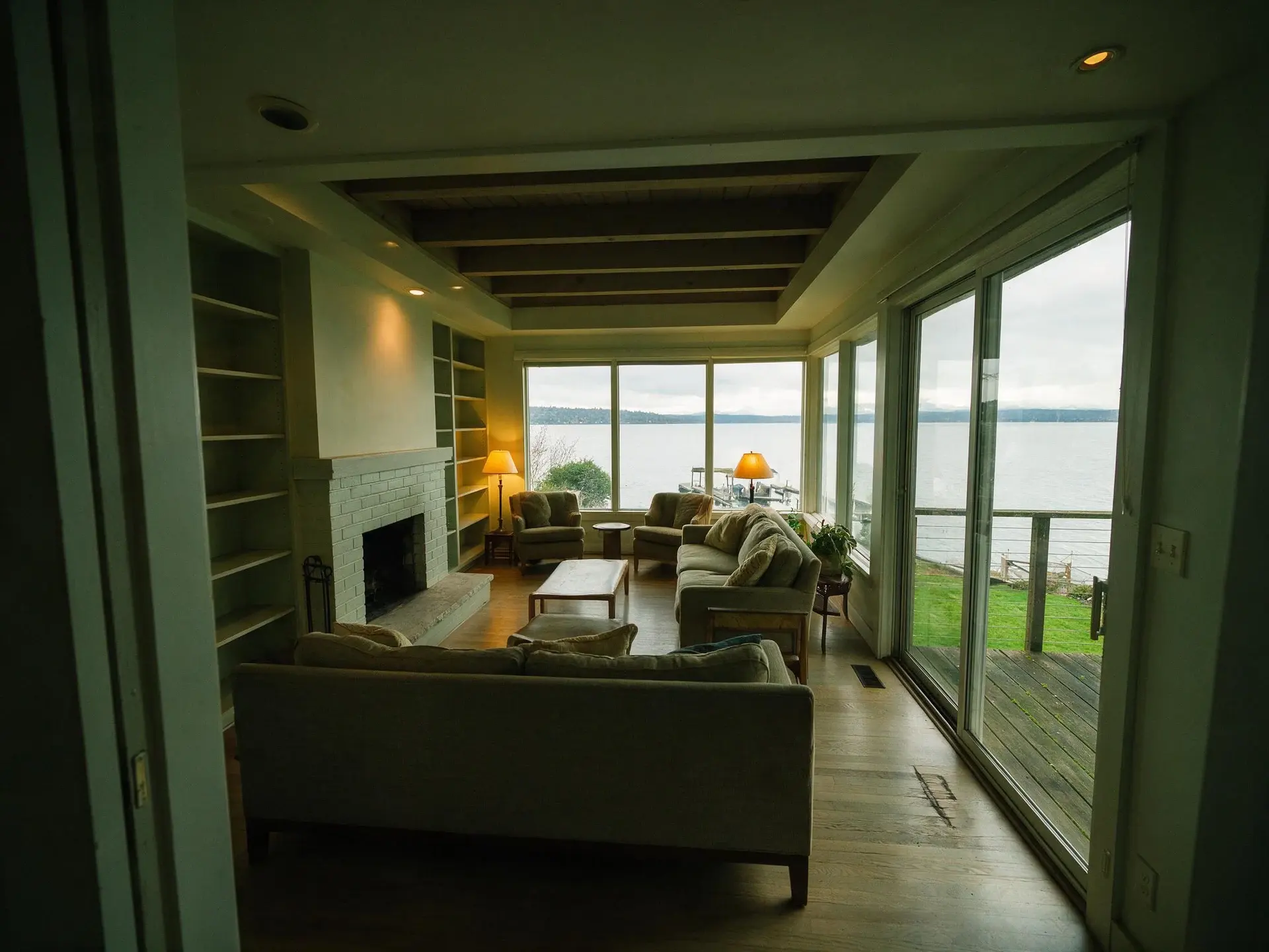 Before and after of a lakefront house living room in Madison Park, Seattle. — original listing photo before editing