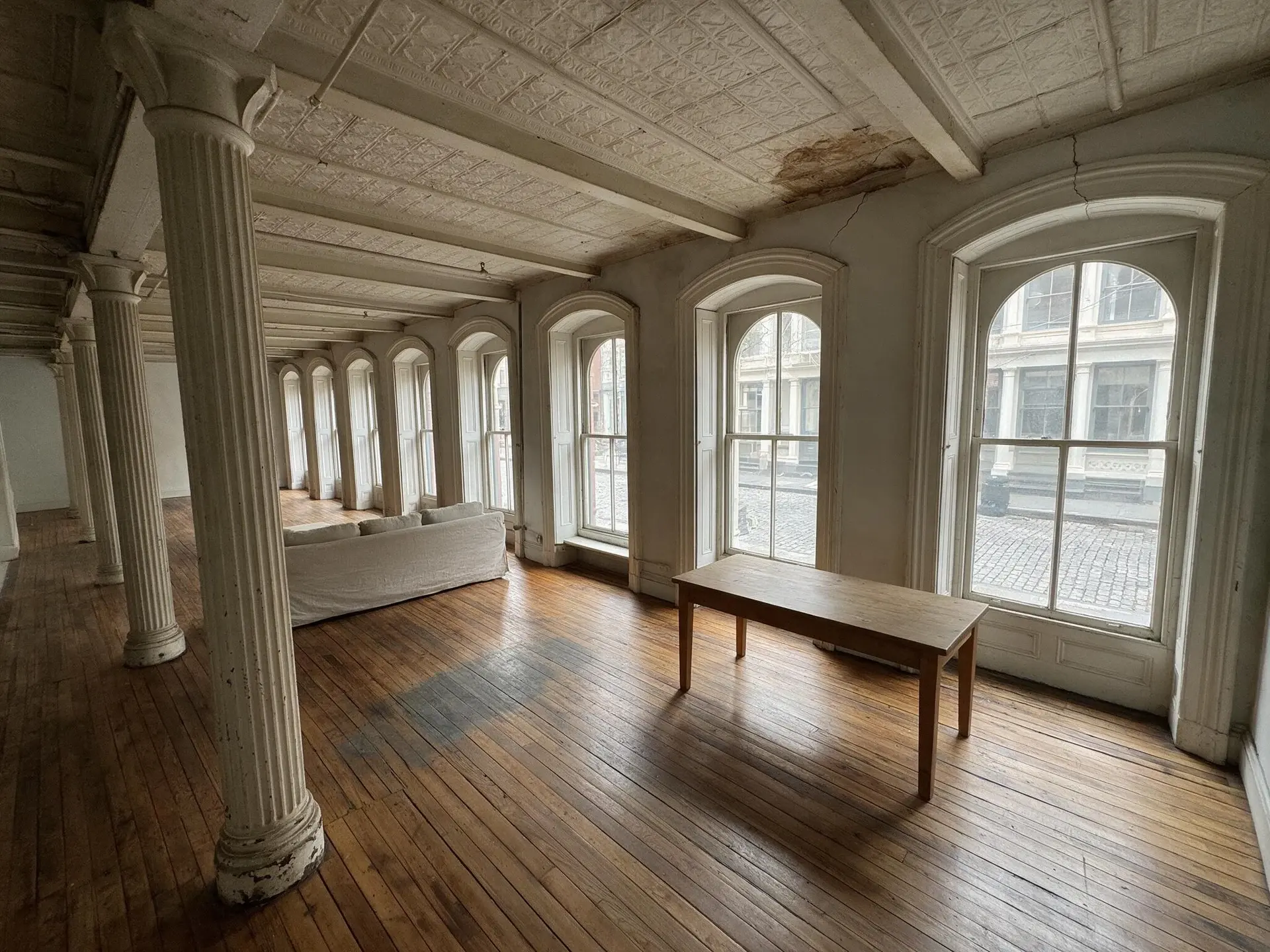 Before and after of a Tribeca cast-iron loft interior in New York with leaning columns straightened — original listing photo before editing