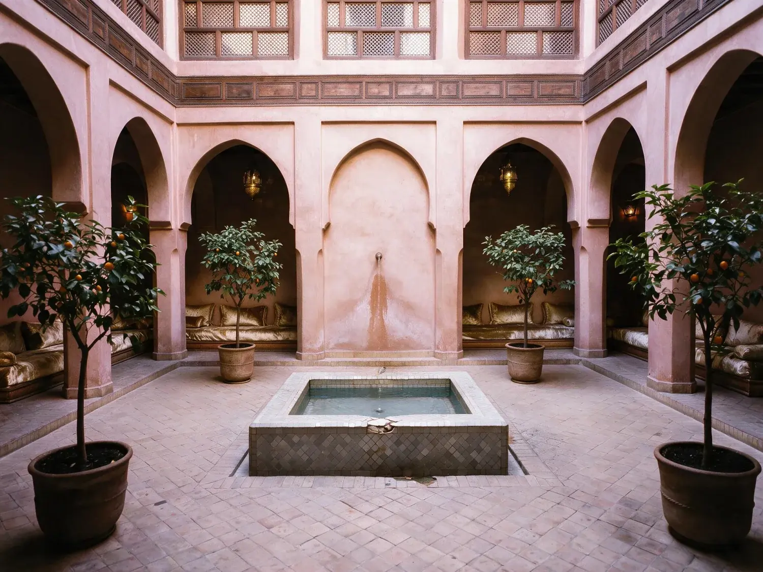 Before and after of a jewel-box marrakech riad courtyard recovers its tile colour and shadow depth, zellige glowing and orange leaves finally readable — enhanced by Plotpane