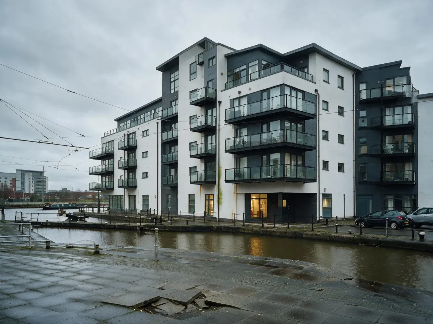 Before and after of a salford quays waterfront modernist apartment block captured under flat pennine overcast — recovered into a rightmove premium hero — enhanced by Plotpane