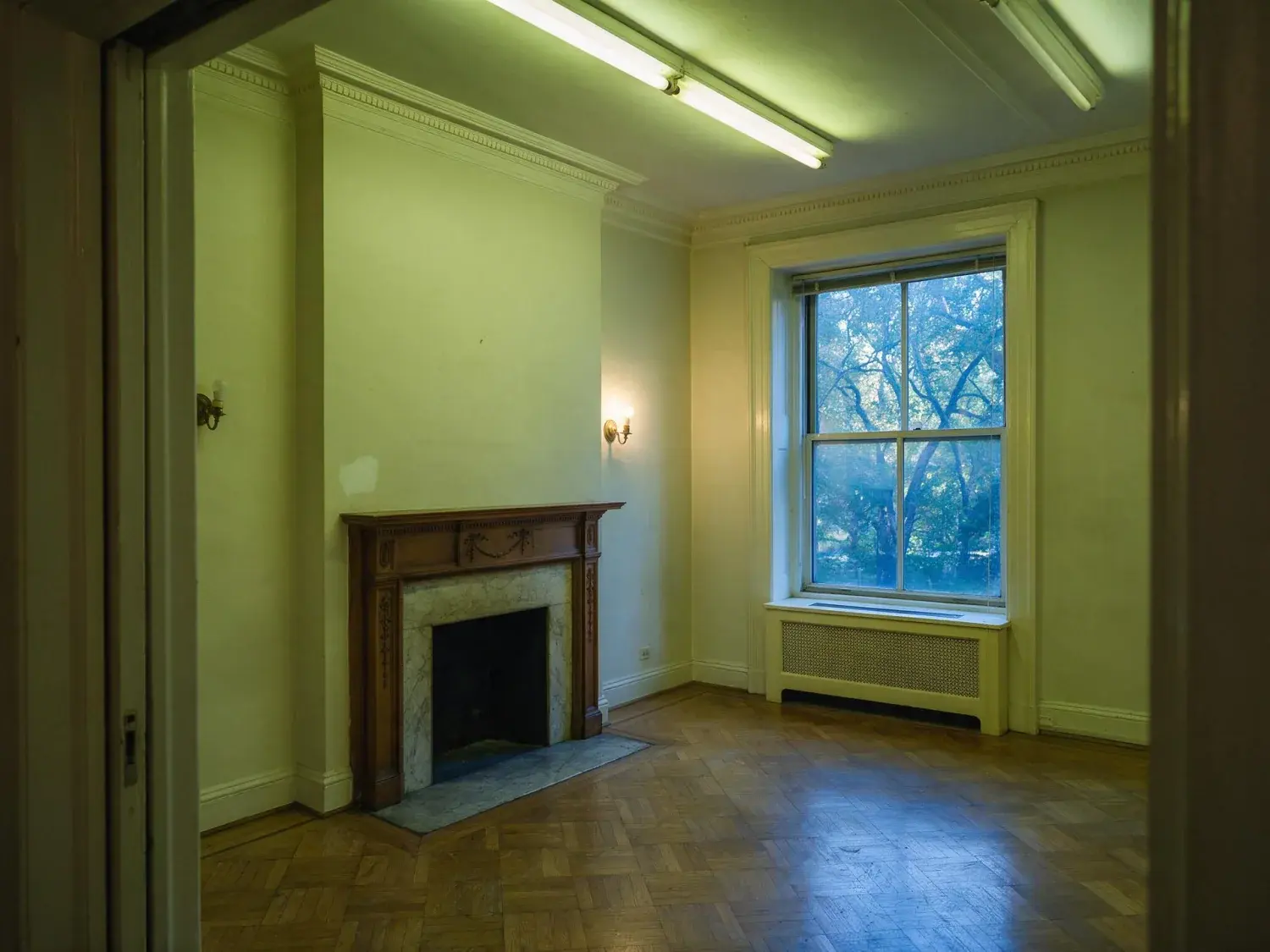 Before and after of a rittenhouse square prewar co-op unit between tenants, a leasing-office phone shot in fluorescent haze restored to marketing-grade apartments.com hero — original listing photo before editing