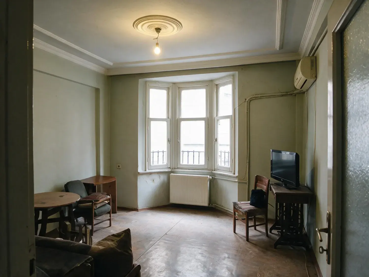 Before and after of a dark alsancak salon on a narrow back street, underexposed against blown-out windows and colour-cast by mixed light — enhanced by Plotpane