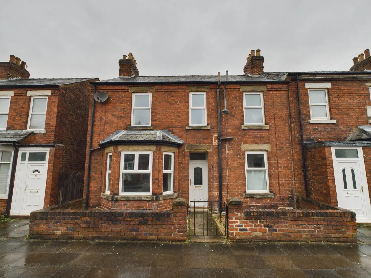 Before and after of a manchester mid-terrace shot under solid grey cloud with no detail in the sky at all — original listing photo before editing