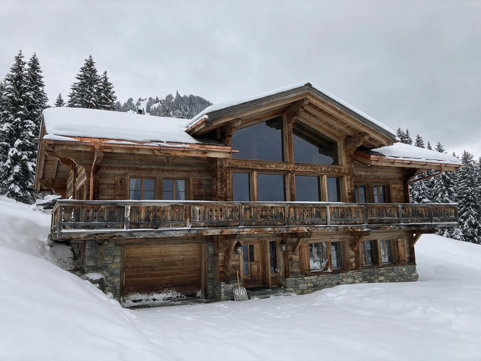 Before: larch chalet in Gstaad snow under a white winter sky, its gable glazing dark