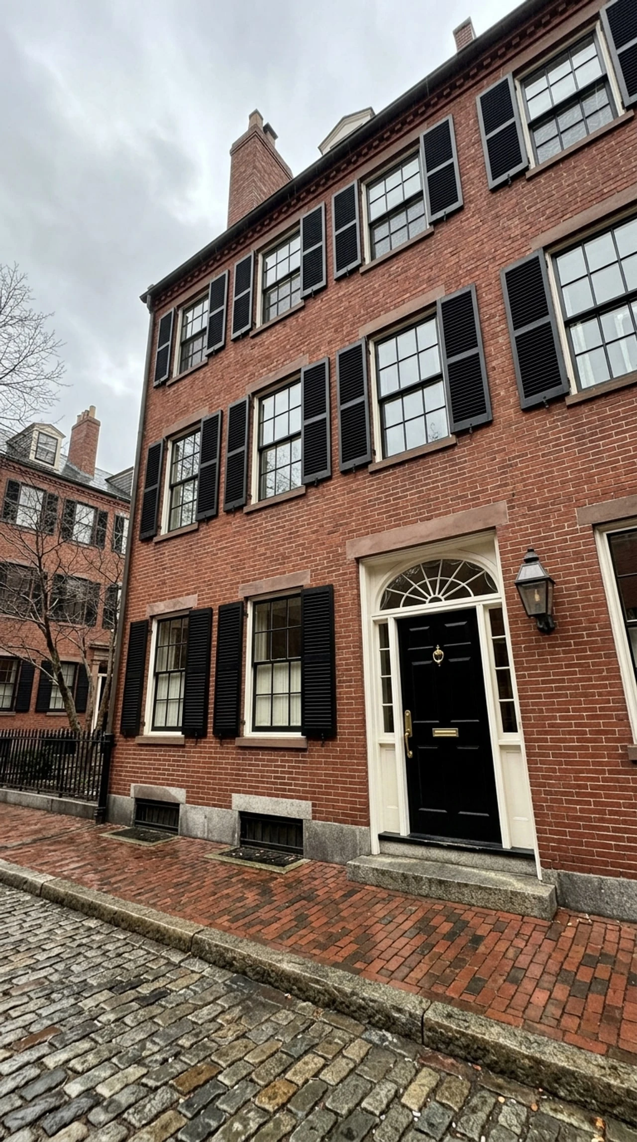 A four-story Beacon Hill Federal townhouse, its leaning phone-shot verticals corrected into a stately symmetrical portrait. — original listing photo before editing