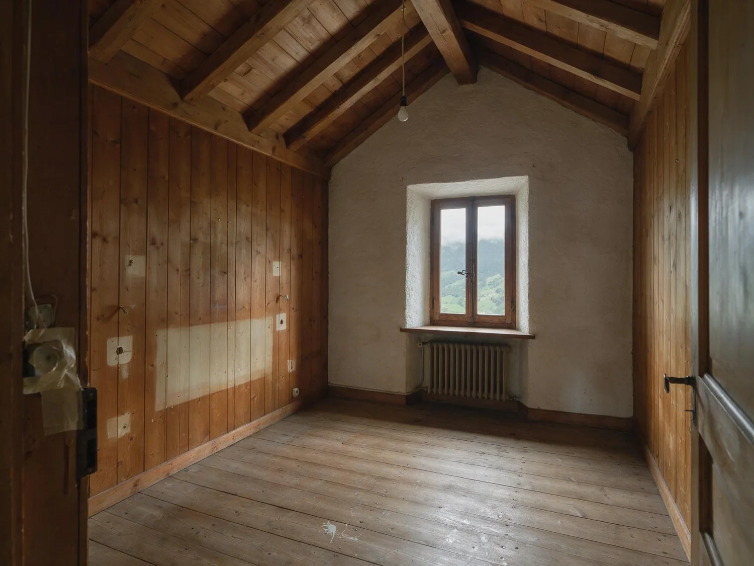 Before virtual staging: empty pine-paneled attic bedroom with exposed rafters, a single window and an old radiator
